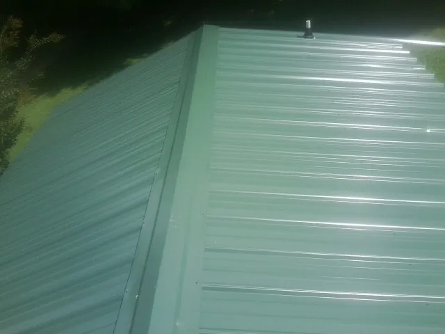 New green metal panels meeting at the ridge of a roof — Flat Roof Repair work by our crew in Braddock