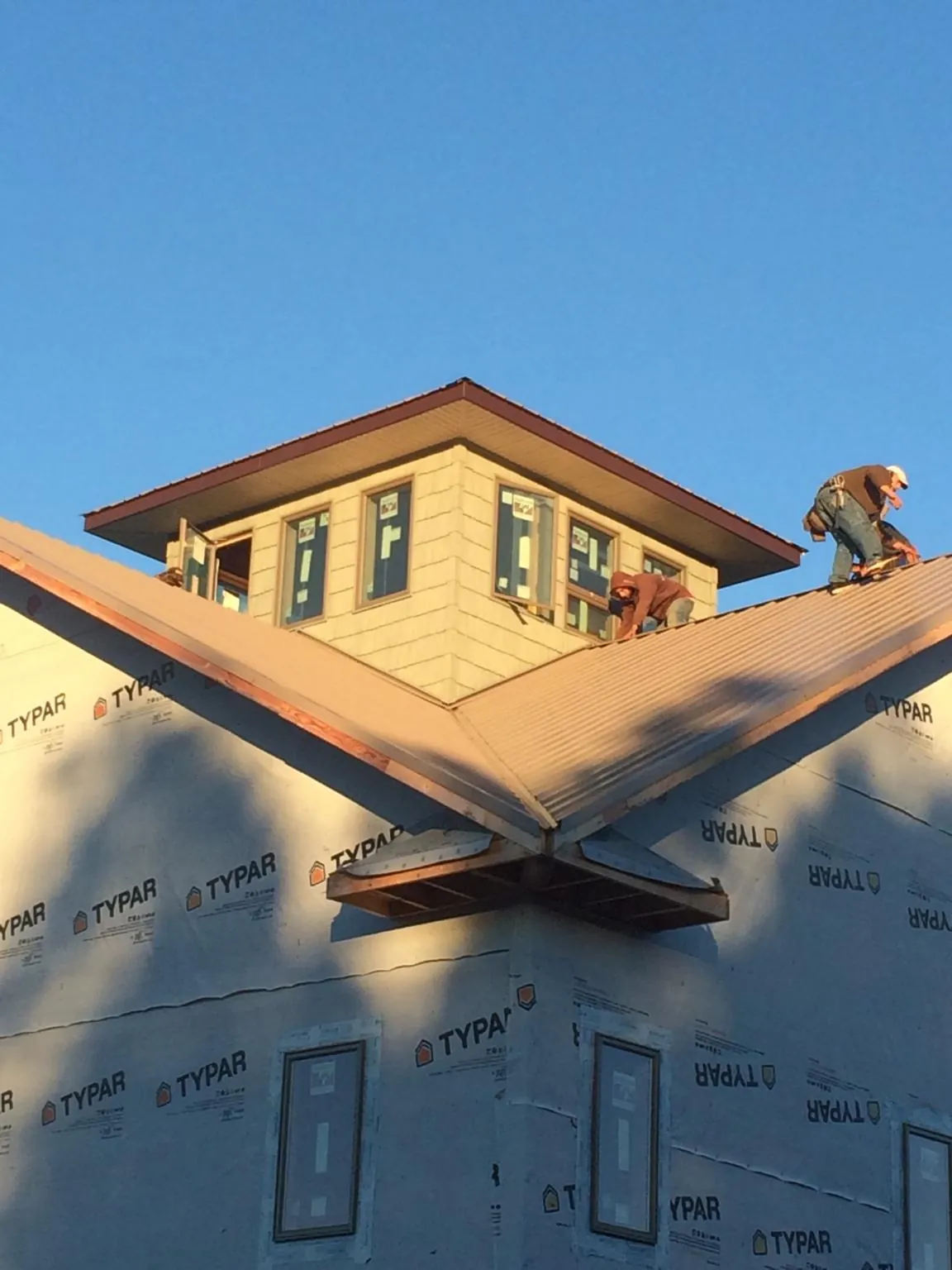 Roofers working around a rooftop cupola on a new metal roof at sunset — Roof Waterproofing in Braddock by Roofing Brothers